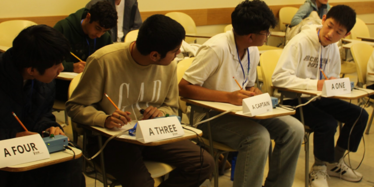 The science bowl team deliberates during a competition. Foreground, from left to right: Richard Peng '27, Anish Roy '27, Sudhanva Belur '27, Ben Zheng '28. Background, left: Kiyan Raisinghani '28. (Archbishop Mitty)