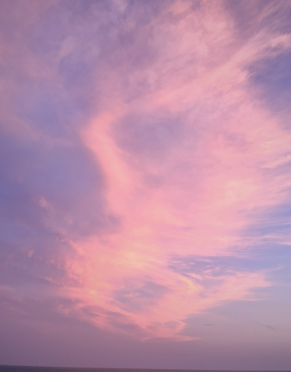 The melting sun’s rays are split in bountiful beauty above the sea onto a summer’s lightly cloudy sky.