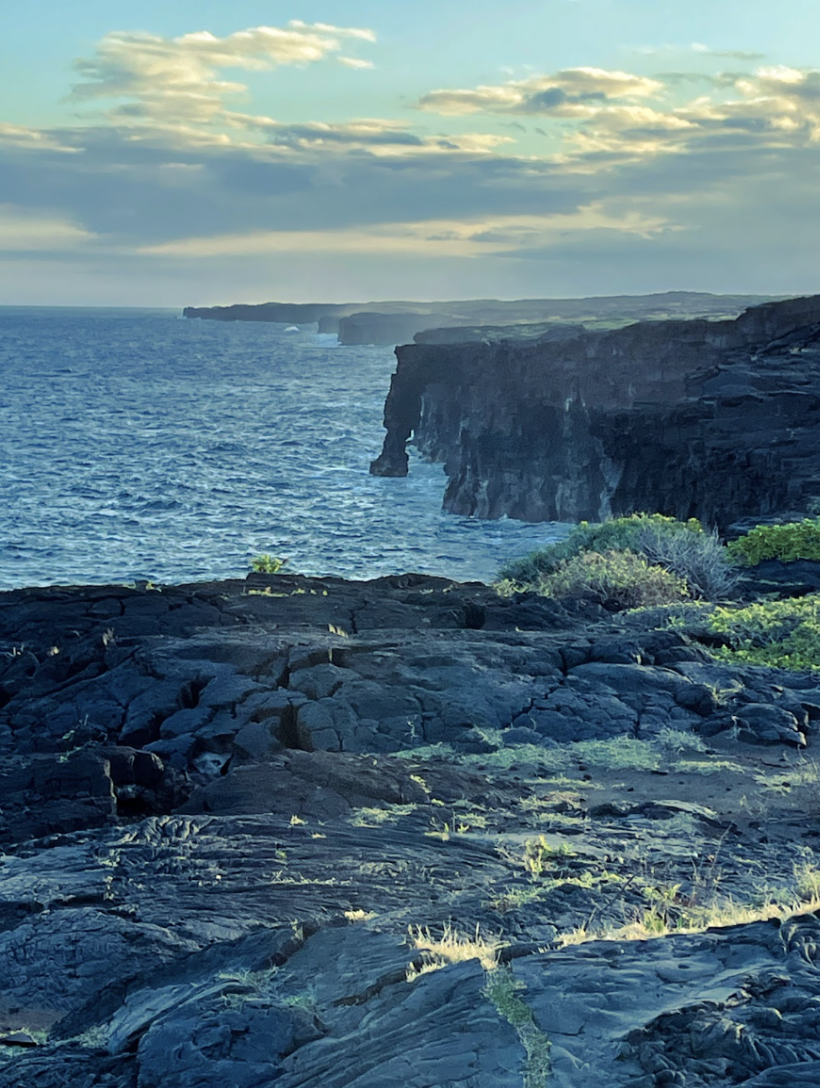 Taken at the rocky sea-side of Hawaii, picturing where the dark lava rocks meet the blue sea. The blue of the sea and the black of the rocks create a photo with a cool temperature.