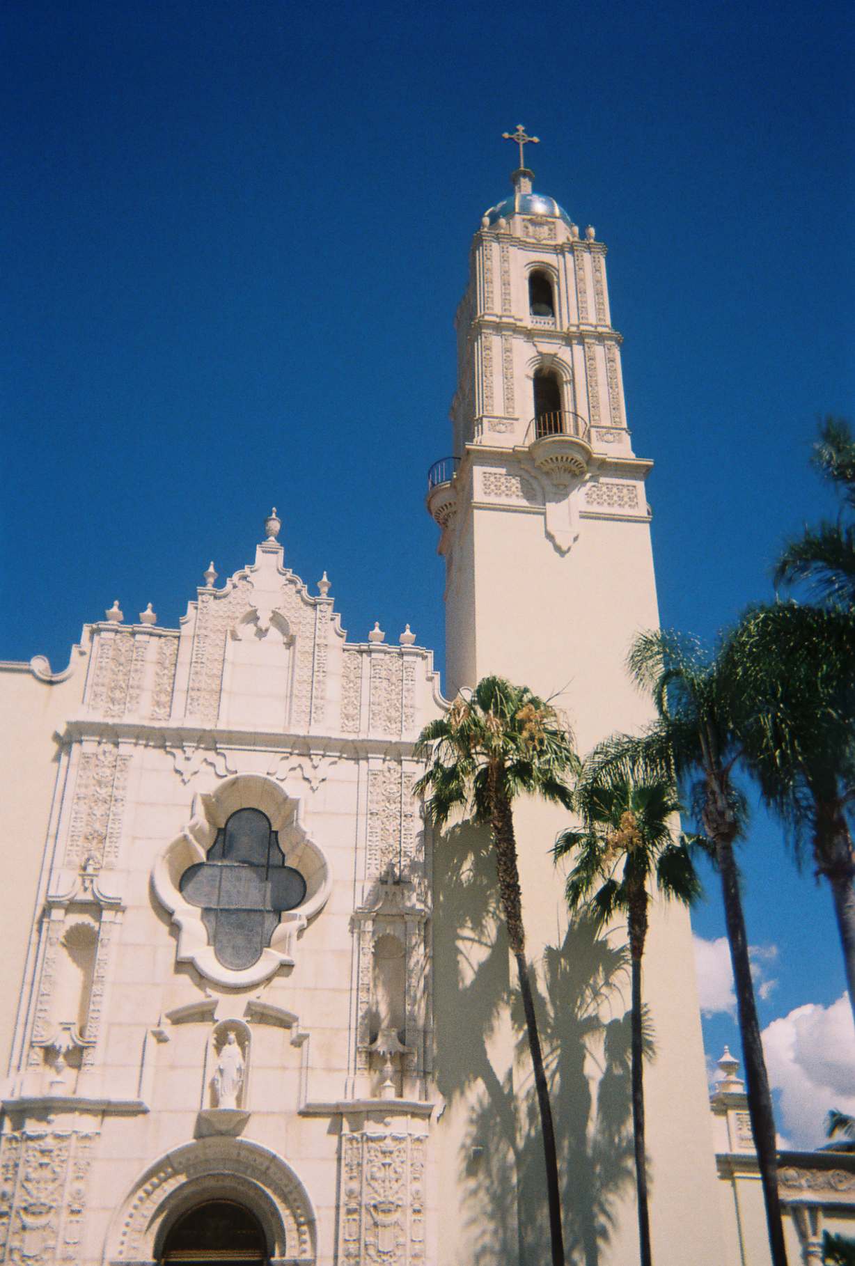 An asymmetrical tower rises above the palm trees to grab at the deep blue sky.
