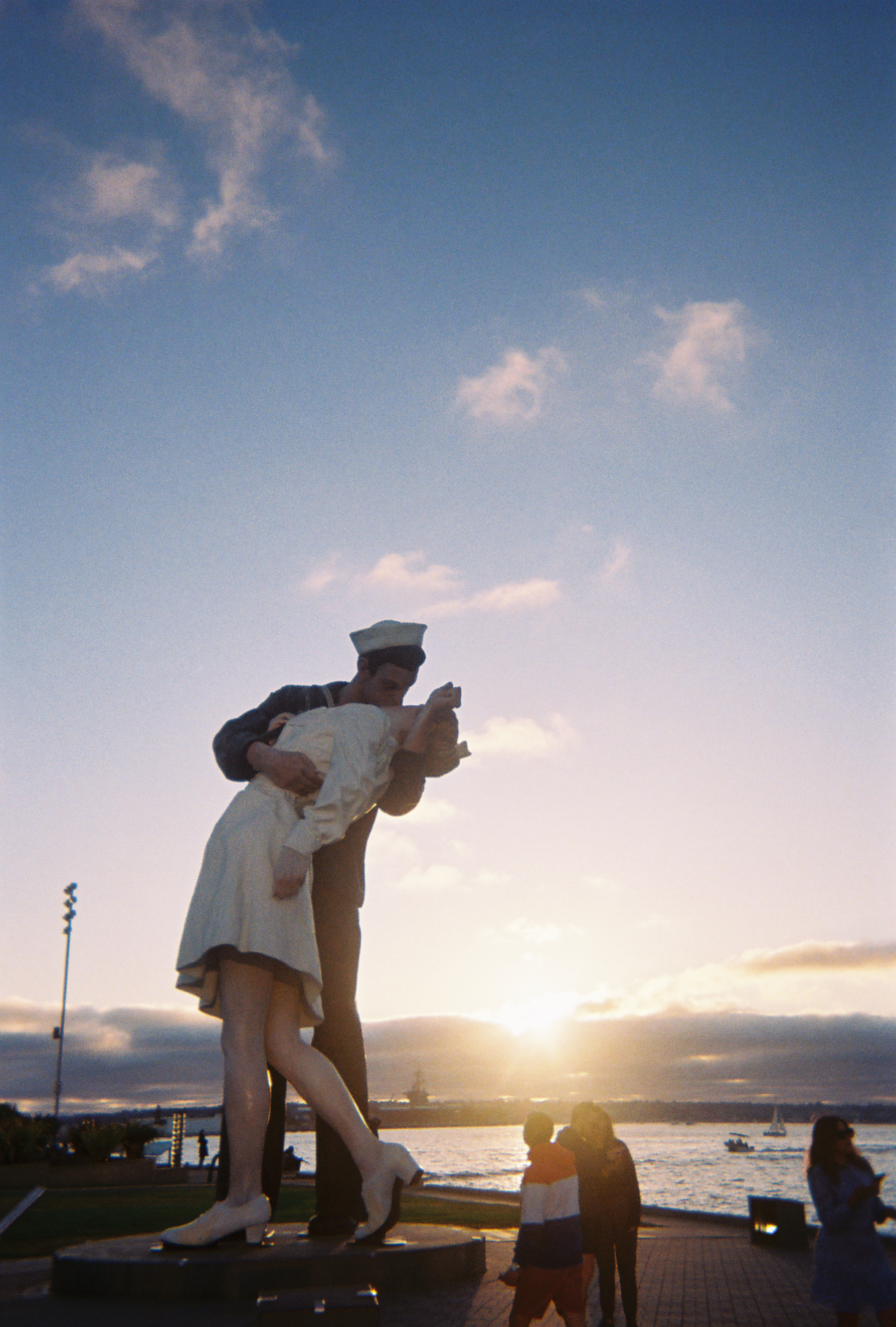 A sailor statue, frozen in time, shares a melting kiss at sunset.